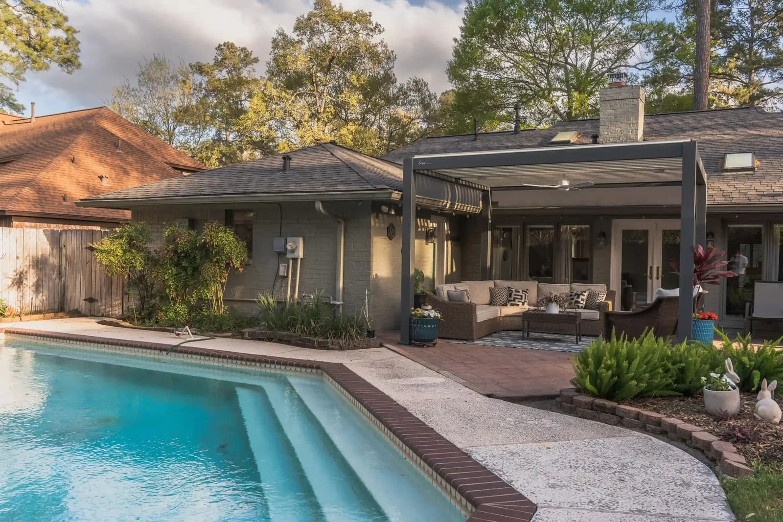 Louvered aluminum pergola shading a lounge beside a swimming pool